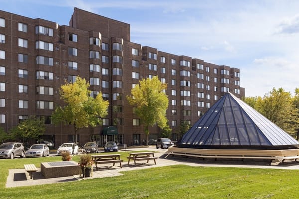 Outdoor view of RidgePointe Senior Living, featuring a grassy area, picnic tables, and a unique pyramid structure.