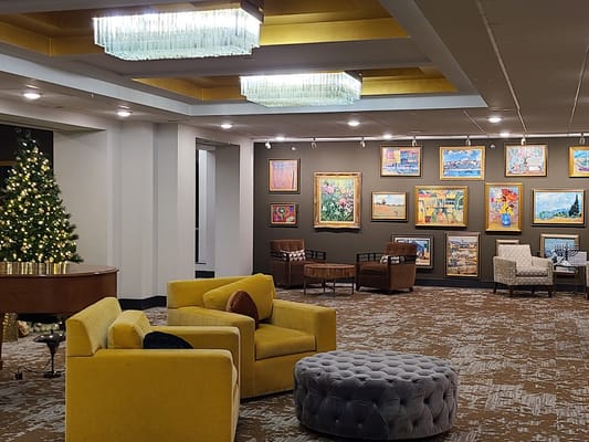 Cozy lounge area with yellow chairs, paintings, and a Christmas tree