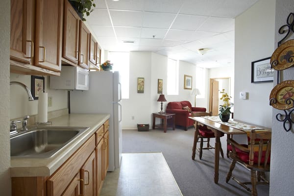 A view of the kitchen and living area in a senior living facility room.