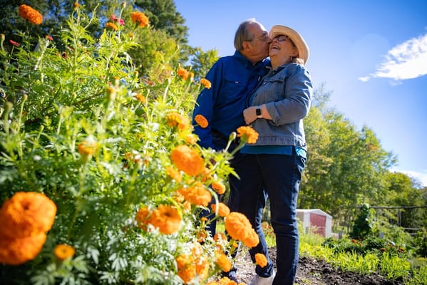 A couple smiling in a garden filled with orange marigolds.
