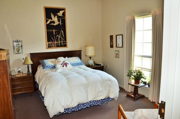 A cozy bedroom with a bed, lamp, and window at Rosewood Villas.