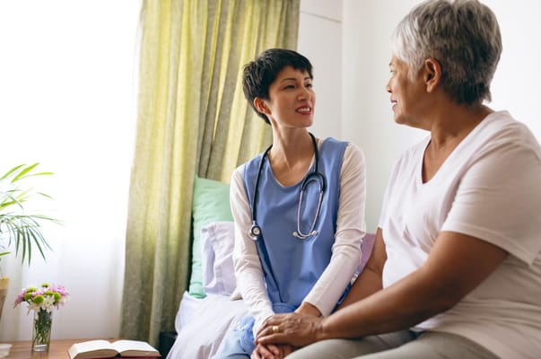 A caregiver and a senior resident smiling and talking in a cozy room.