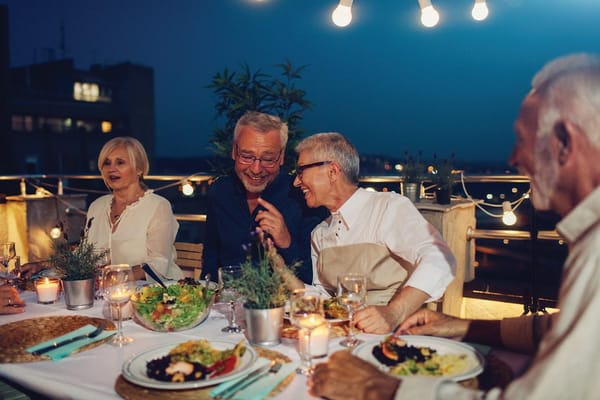 A joyful group of seniors enjoying dinner outdoors at night.