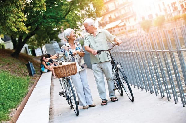 Elderly couple walking with bicycles by a waterfront