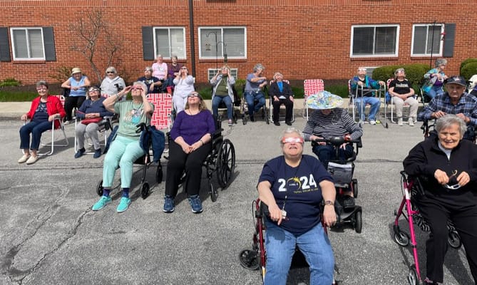 Residents of Sanders Glen Assisted Living watching a solar eclipse outdoors.