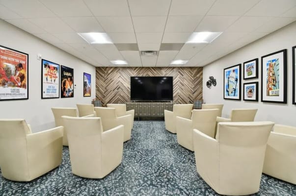 Comfortable seating arranged in a media room with wall art and a TV.