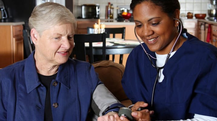 Healthcare worker assisting a senior resident with health monitoring