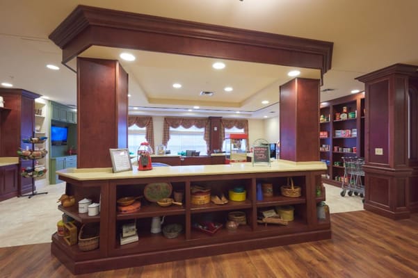 Spacious common area with a service counter and shelves in a senior living facility.