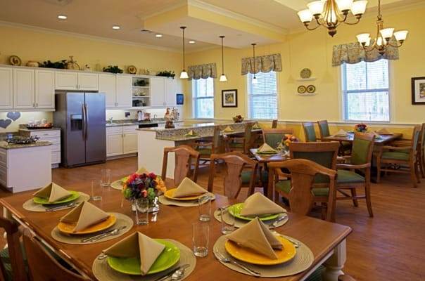 Bright dining room with neatly set tables and a kitchen area