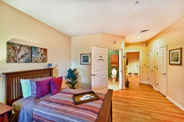 A well-furnished bedroom with a bed, decorative pillows, and two doors leading to other spaces.