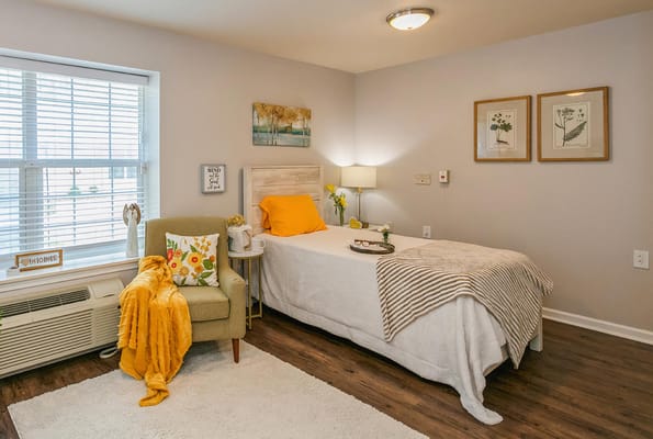 A cozy bedroom with a bed, chair, and decorative elements.