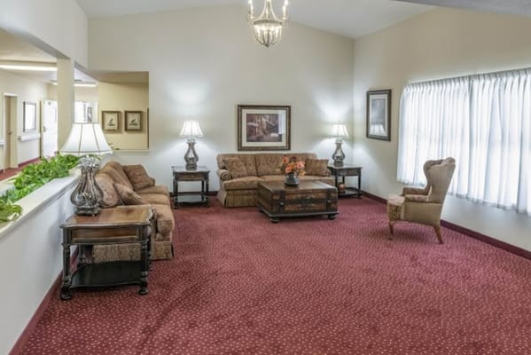 Cozy lounge with sofas, coffee table, and lamps in a senior living facility.