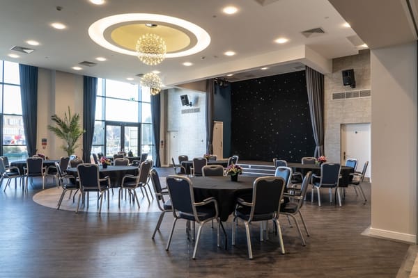 Spacious dining area with round tables and black tablecloths.