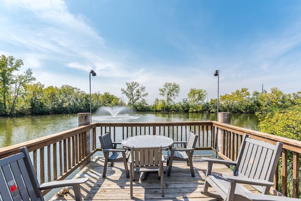 Deck overlooking a serene pond in a landscaped area