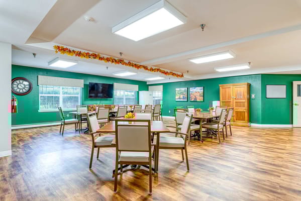 Bright dining area with tables and chairs, decorated with autumn leaves.