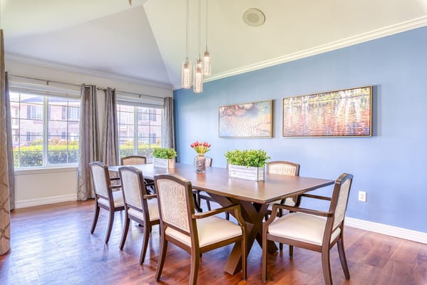 Bright dining area with a large table, plants, and artwork.