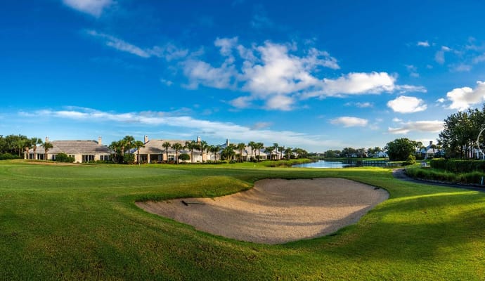 View of golf course with sandy bunker and residential buildings