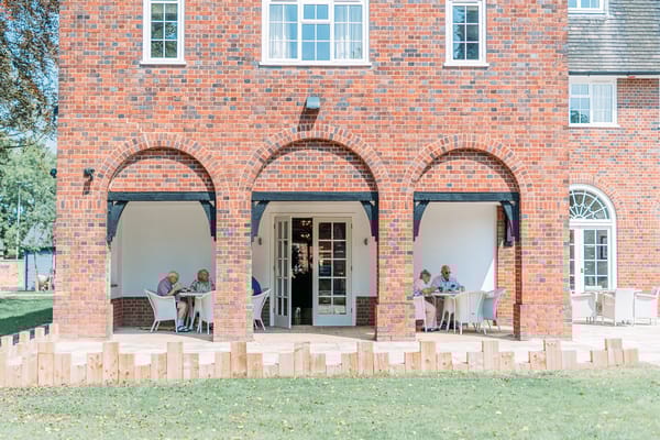 Seniors enjoying meals in an outdoor dining area under arches