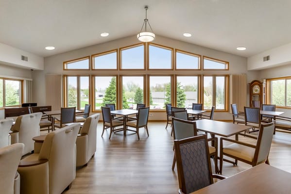 Bright common room with tables and chairs, large windows overlooking the outdoors
