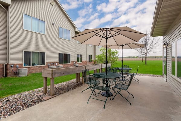 Patio area with tables and umbrellas at South Grove Lodge Senior Living