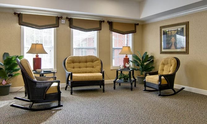 Lounge area with rocking chairs and lamps in a senior living facility.