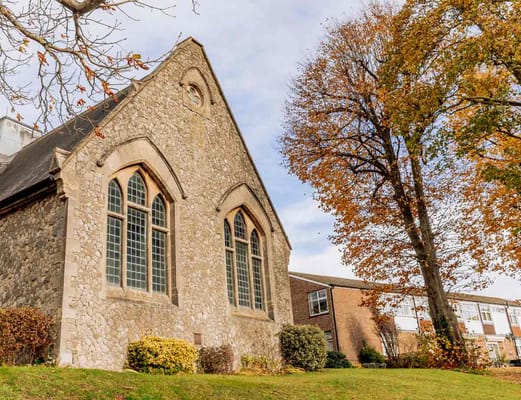 Stone building with large windows next to autumn trees