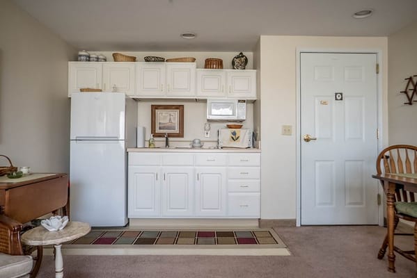 Compact kitchenette with white cabinets and appliances