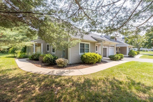 Side view of a residential building with a walkway surrounded by greenery.