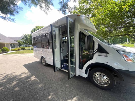 A bus parked outside Southwick Village senior living facility with doors open.
