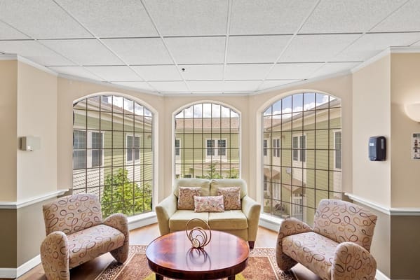 Bright sunroom with comfortable seating and windows overlooking a garden.