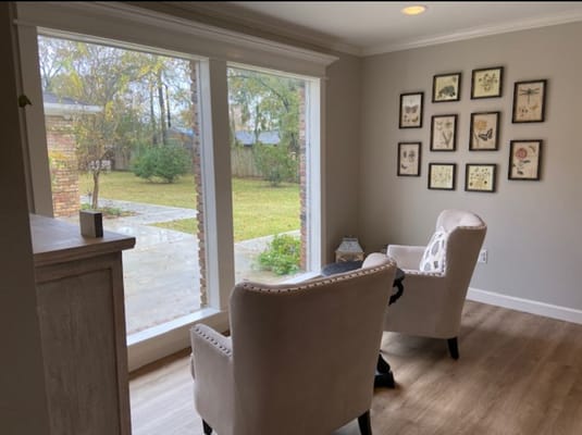 A cozy living room with two chairs and large windows overlooking a garden.