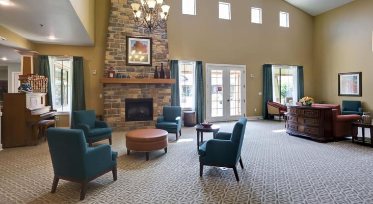 Cozy lounge with a fireplace and seating in Stonefield Assisted Living