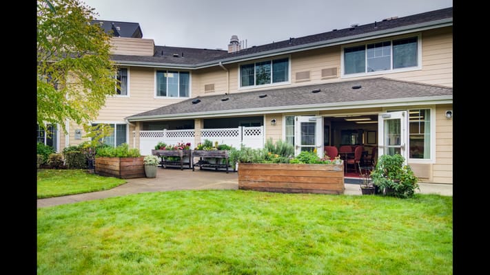 Outdoor garden area with flower planters and lawn at Stoneybrook Senior Living.