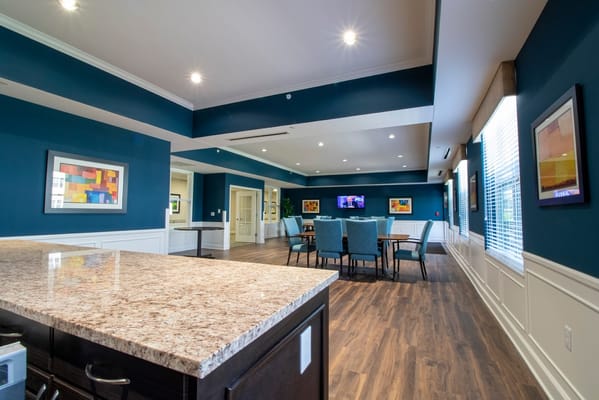 Spacious common area with tables and chairs, blue walls, and artwork