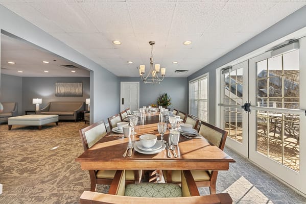 Long dining table set with dishes and cutlery in a well-lit room.