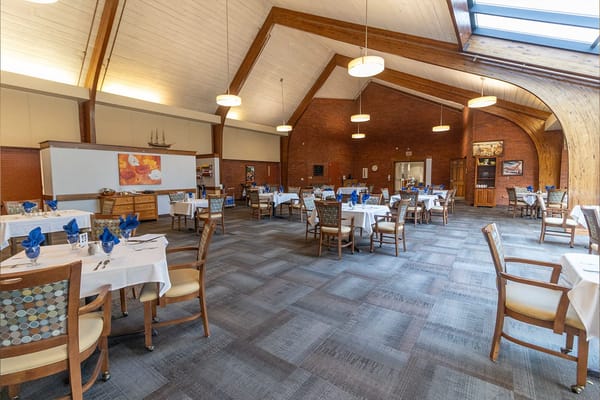 Spacious dining room with round tables set for a meal.