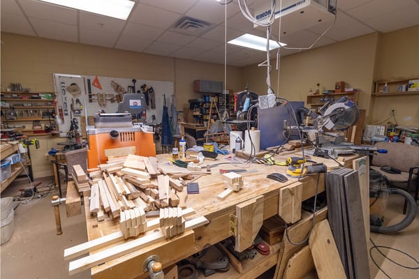 A cluttered woodworking shop with tools and wooden pieces.