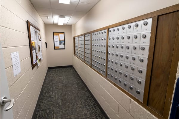 A hallway with mailboxes and bulletin board in a senior living facility