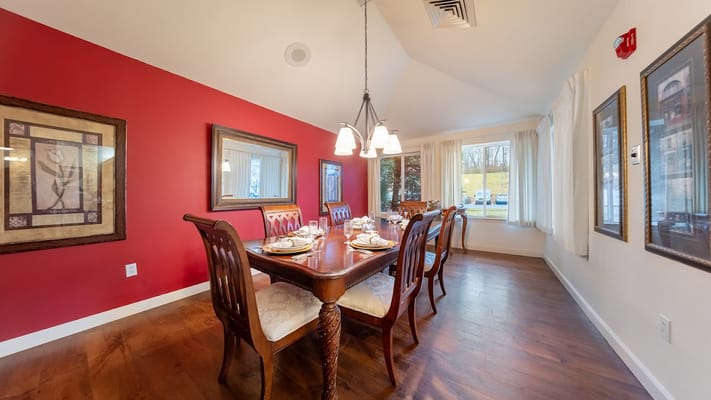 Dining room with a wooden table set for a meal and red accent wall.
