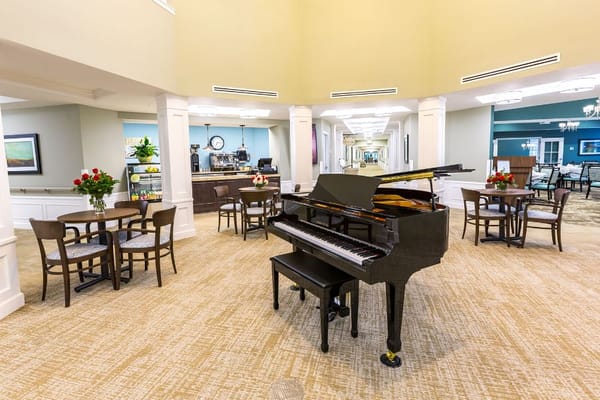 Piano in a community room with tables and chairs
