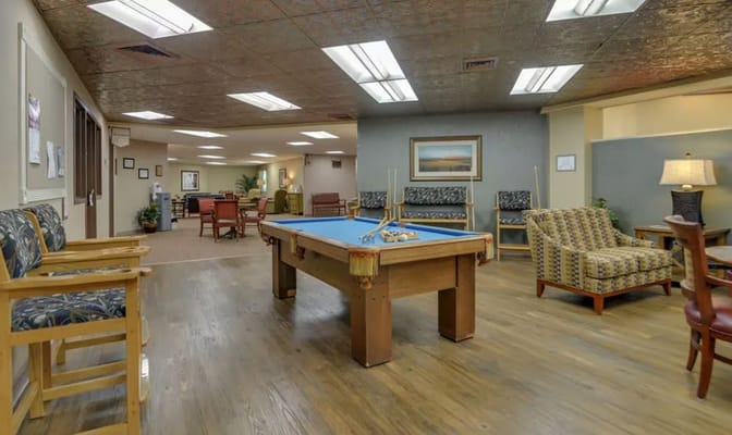 Interior view of the billiards room with a pool table and seating areas.