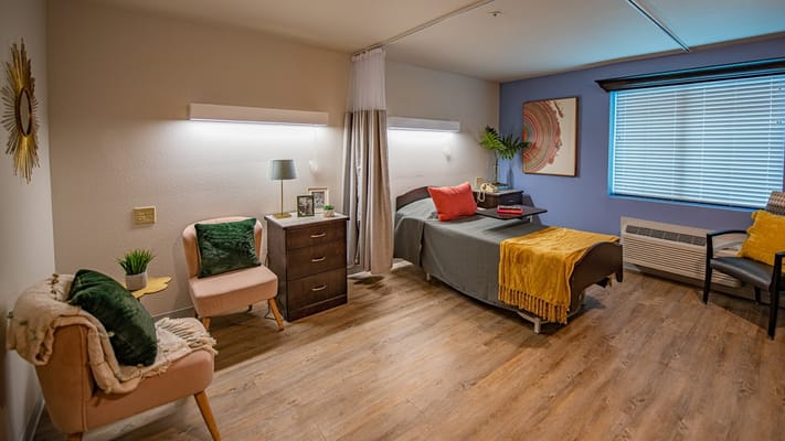 Comfortable and well-furnished senior living room with cozy chairs and a bed