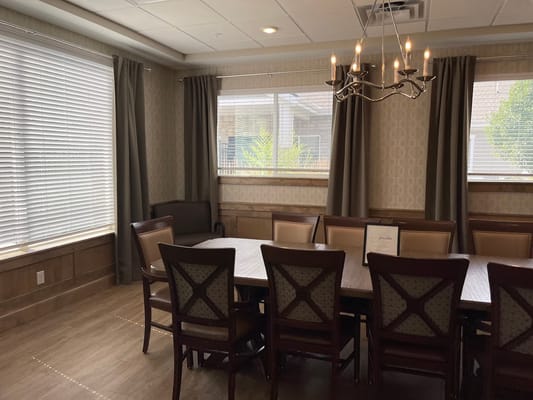 Cozy dining room with a large table and chairs, natural light from windows.
