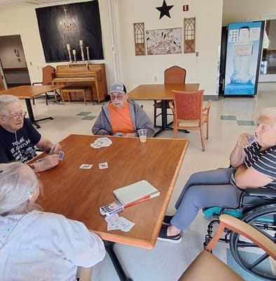 Four seniors playing cards in a cozy common area