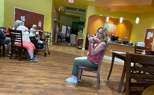 A staff member interacting with residents in the common area of Sunset Ridge Rehabilitation and Nursing Center.