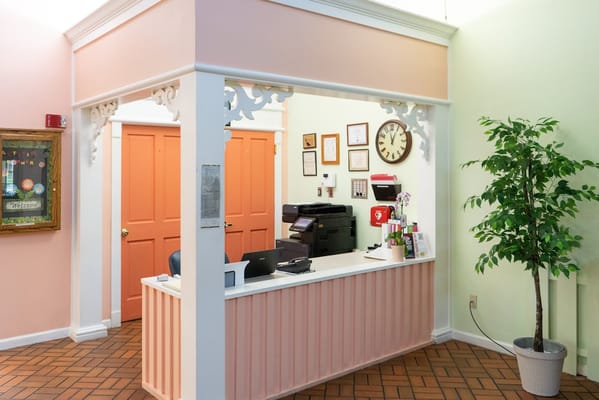 Reception desk with colorful walls and a plant.