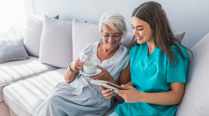 A staff member and a resident sharing a joyful moment on a couch.