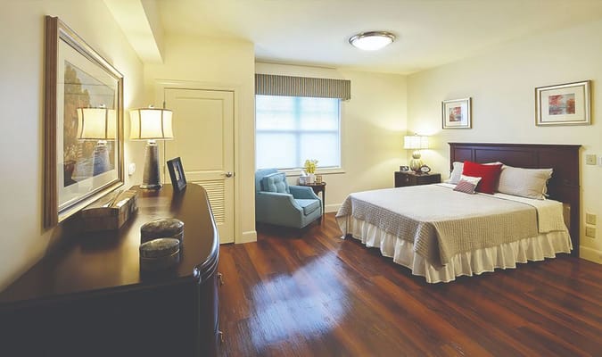 A well-decorated bedroom featuring a bed, armchair, and lamps.