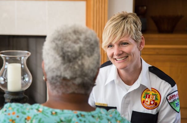 A caregiver smiling and talking to a resident in a cozy setting.