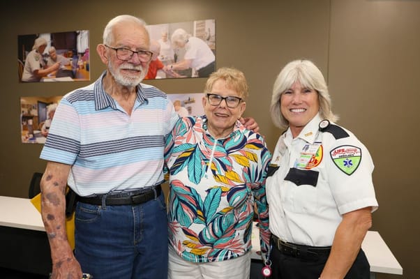 Three smiling individuals posing together in a community space